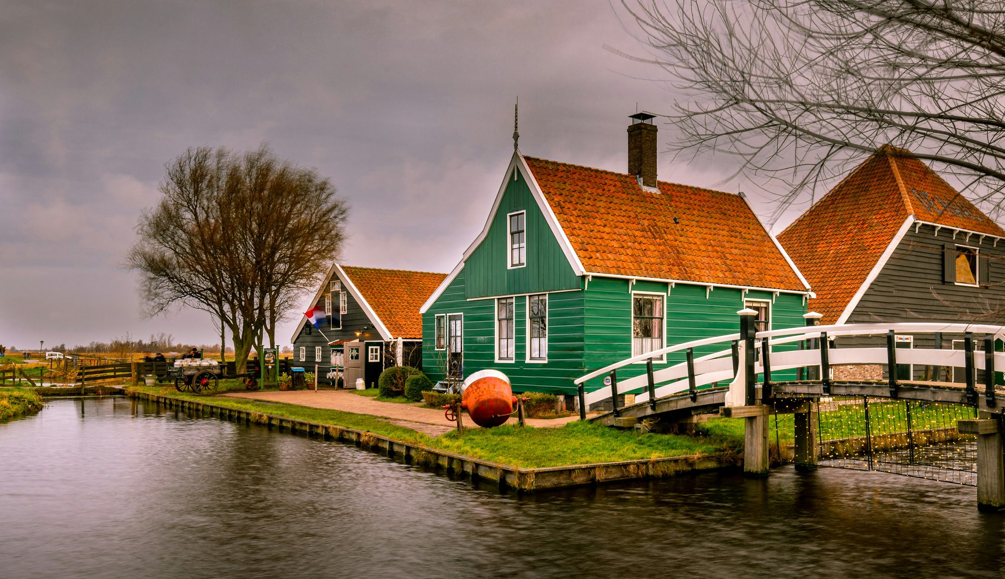 Groen houten dorpshuisje met brug over het kanaal